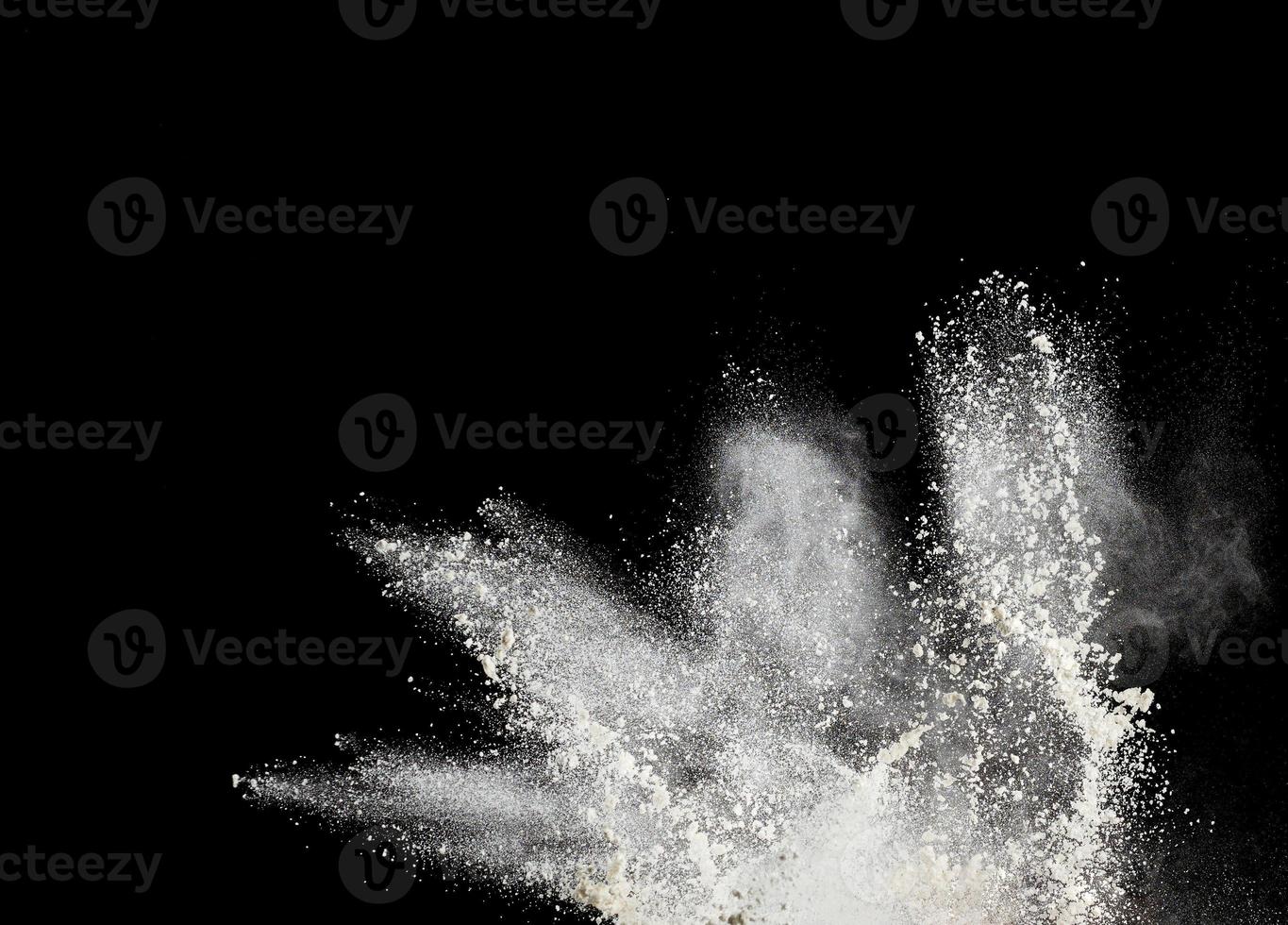 cloud of white wheat flour on a black background, particles fly in different directions photo