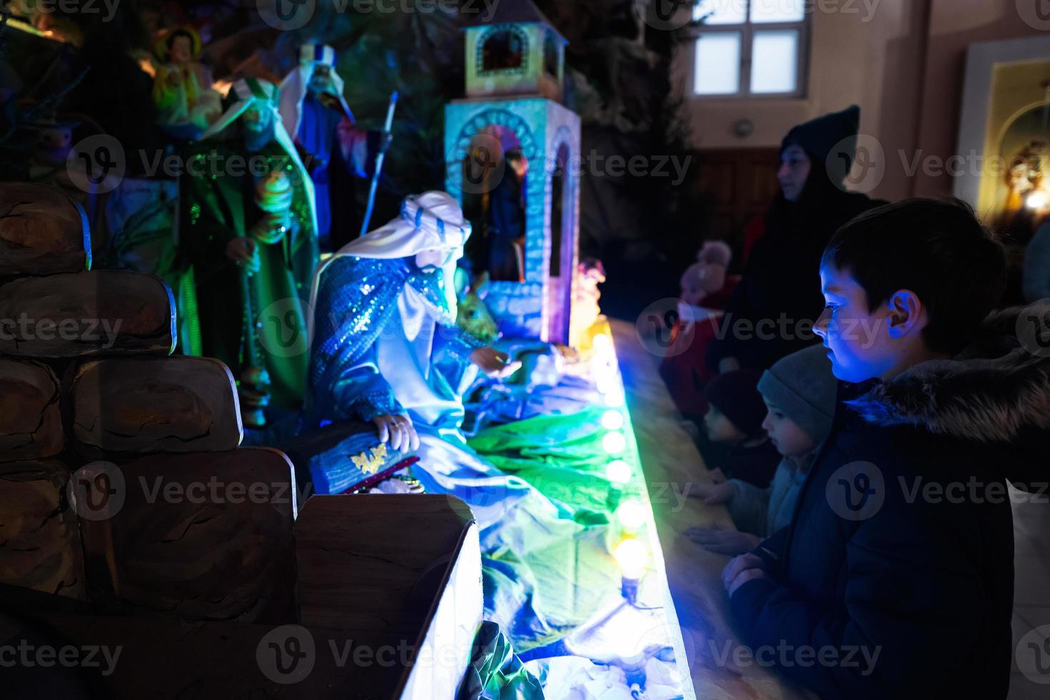Mother with three children visit Christmas nativity crib scene in church. photo