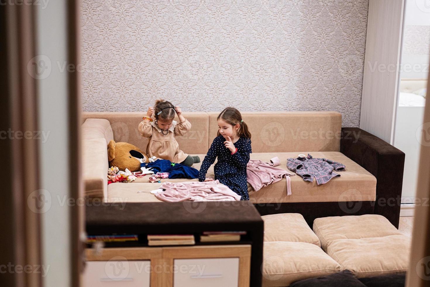 Two sisters are choosing clothes from the wardrobe at home on the sofa. photo