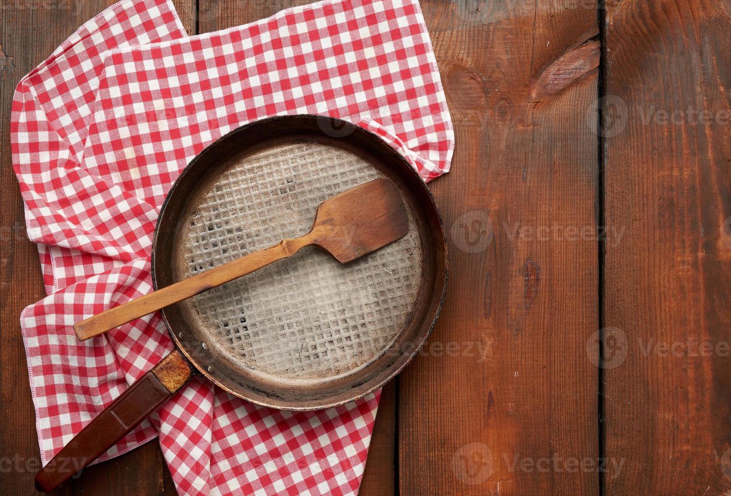 empty round frying pan with handle on brown wooden table photo