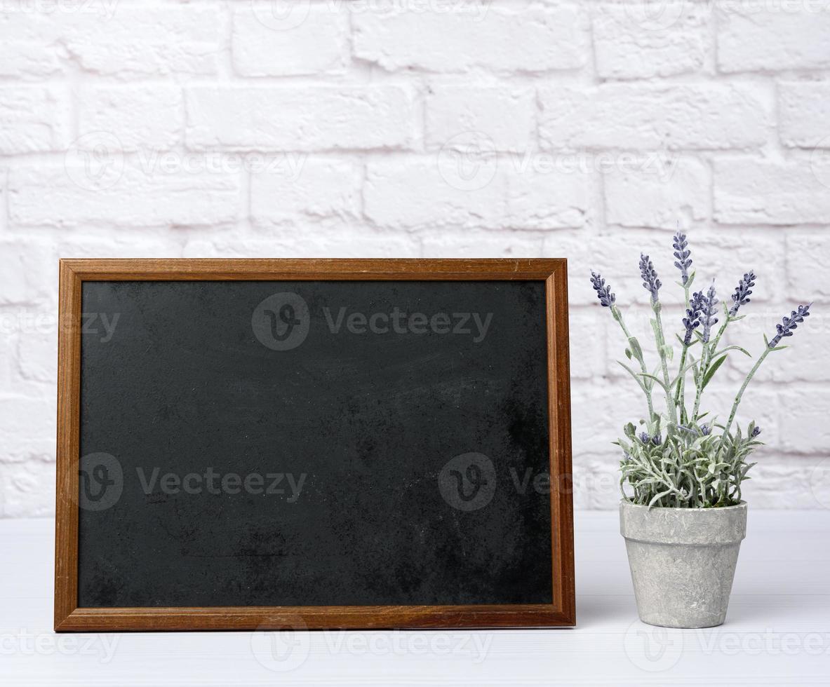 empty wood frame with black background, behind white brick wall photo