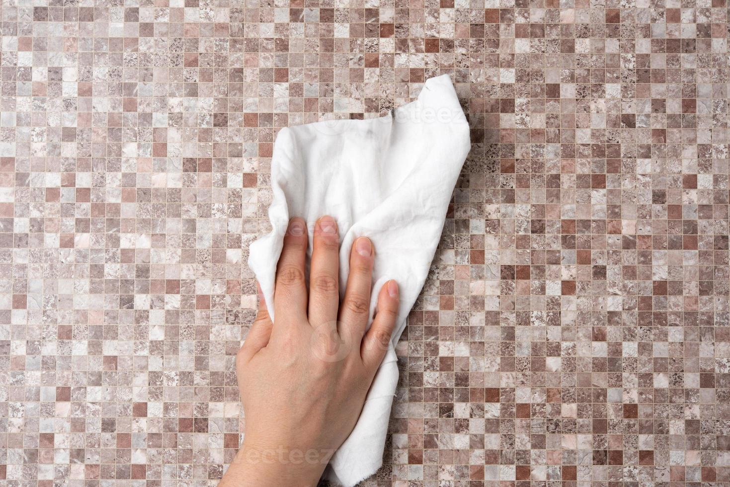 female hand wipes a brown table with a white rag photo