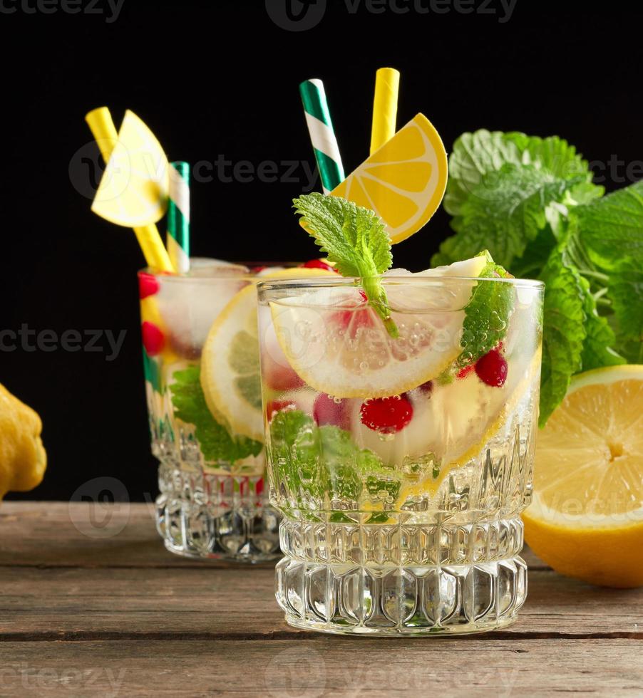 transparent glass with lemonade and pieces of ice, red berries photo