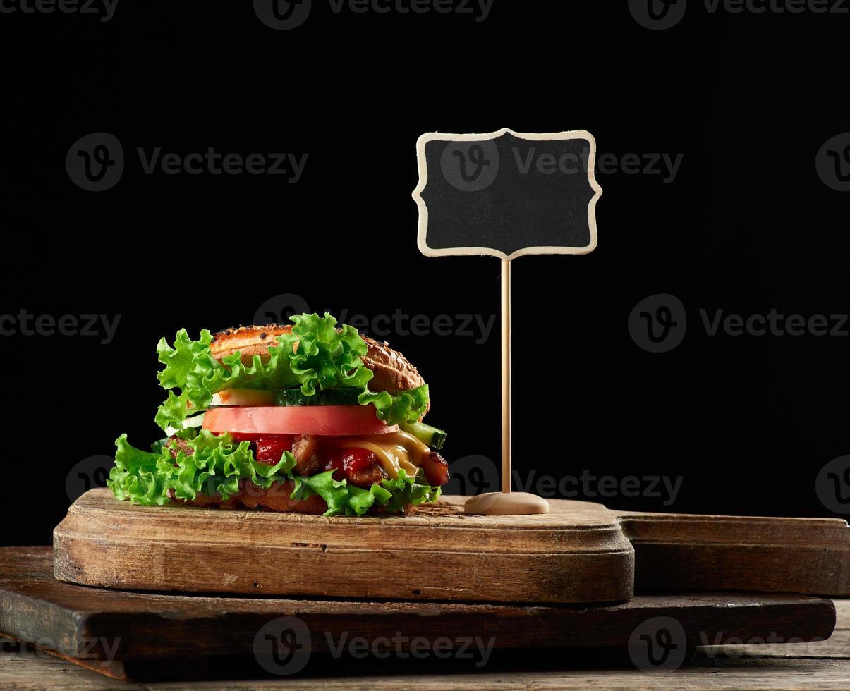 cheeseburger with minced meat, green lettuce and ketchup on a wooden brown kitchen board photo