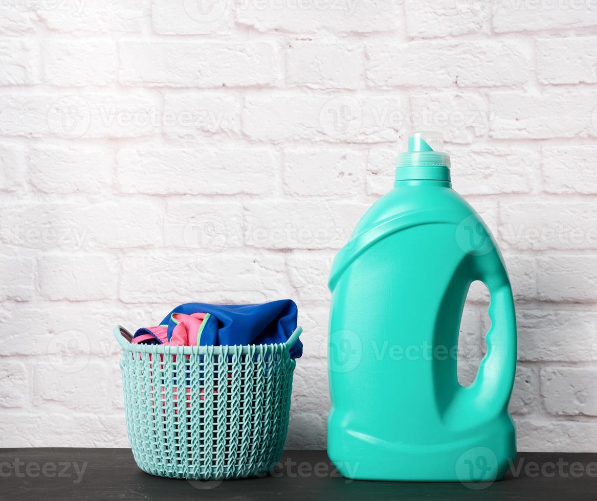 plastic round laundry basket and green bottle with liquid laundry powder photo