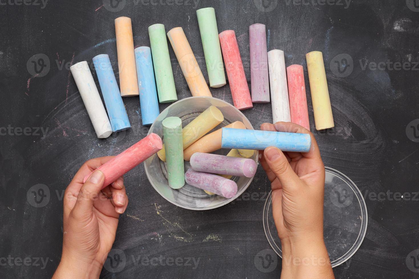 multicolored chalk in a plastic bucket on a black background photo