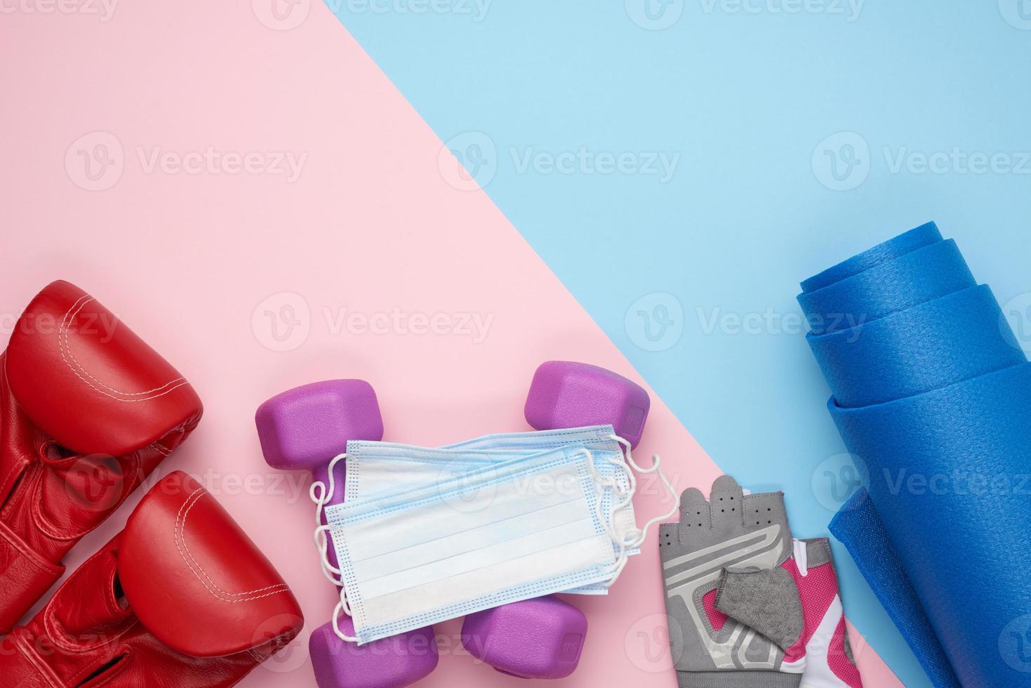 pair of red leather boxing gloves, a blue neoprene mat, a medical face mask and a pair of dumbbells photo
