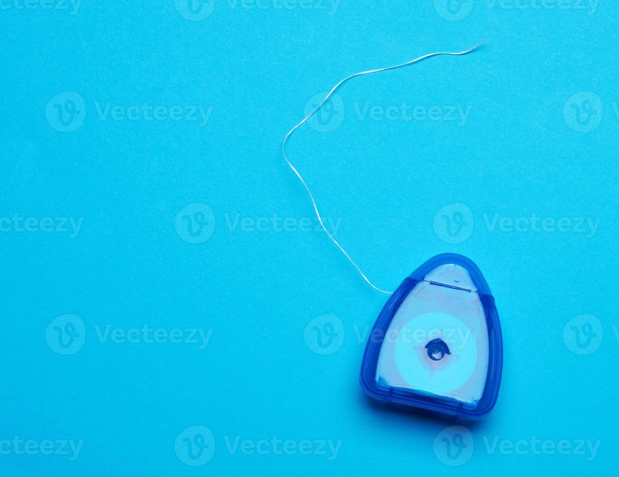 blue plastic packaging with dental floss on a blue background photo