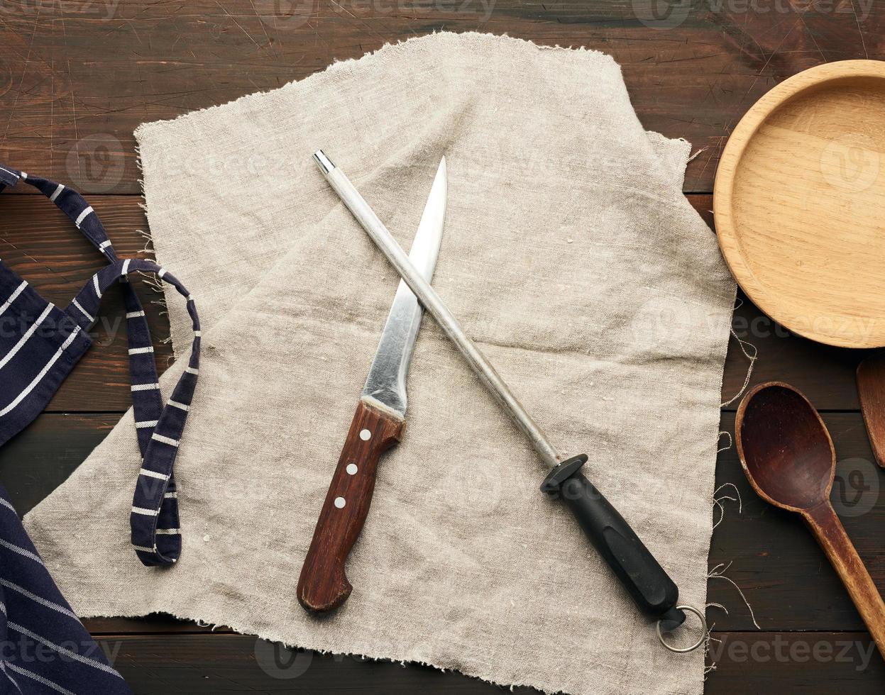 sharp knife and sharpener with a handle on a wooden background photo