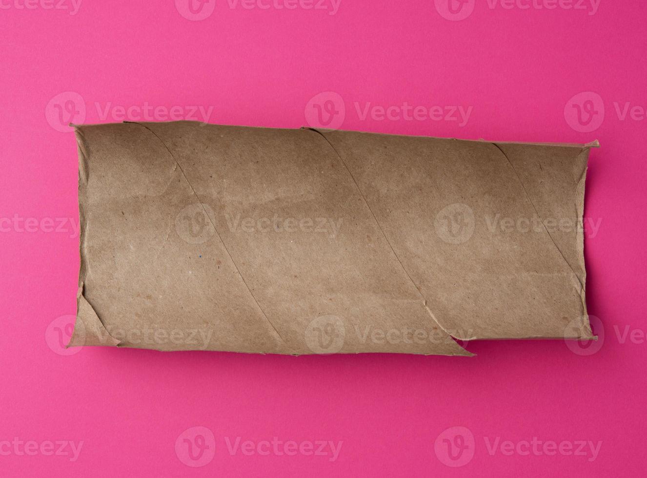 torn piece of brown paper on pink background photo