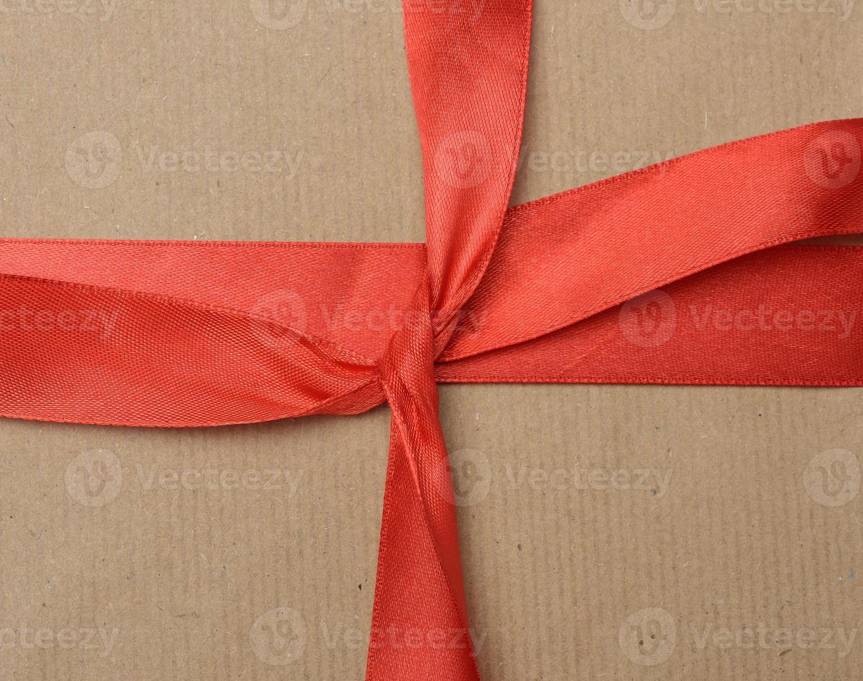 knotted red silk ribbon on brown kraft paper background photo