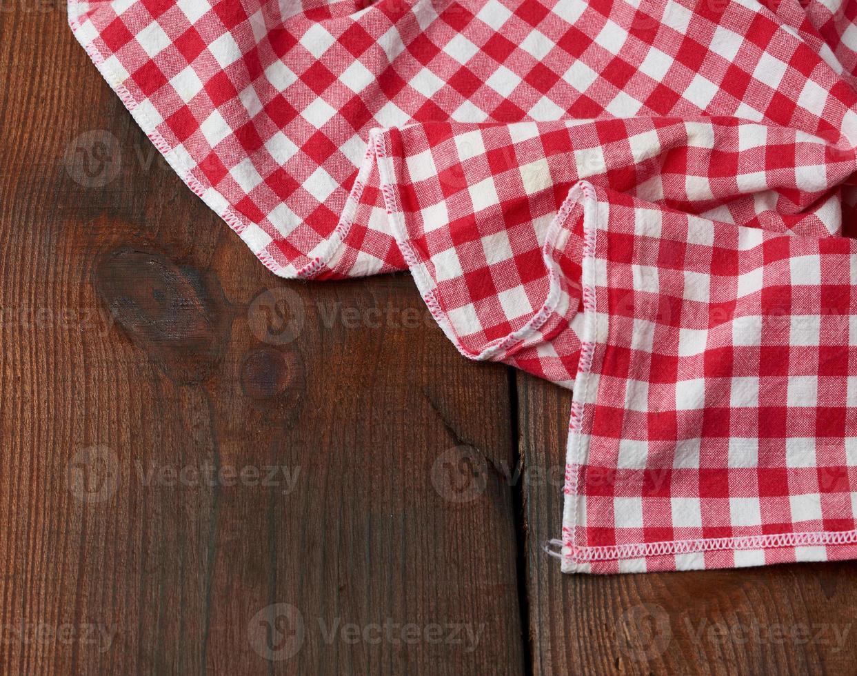 toalla de cocina textil roja y blanca sobre un fondo de madera marrón de tablas viejas foto