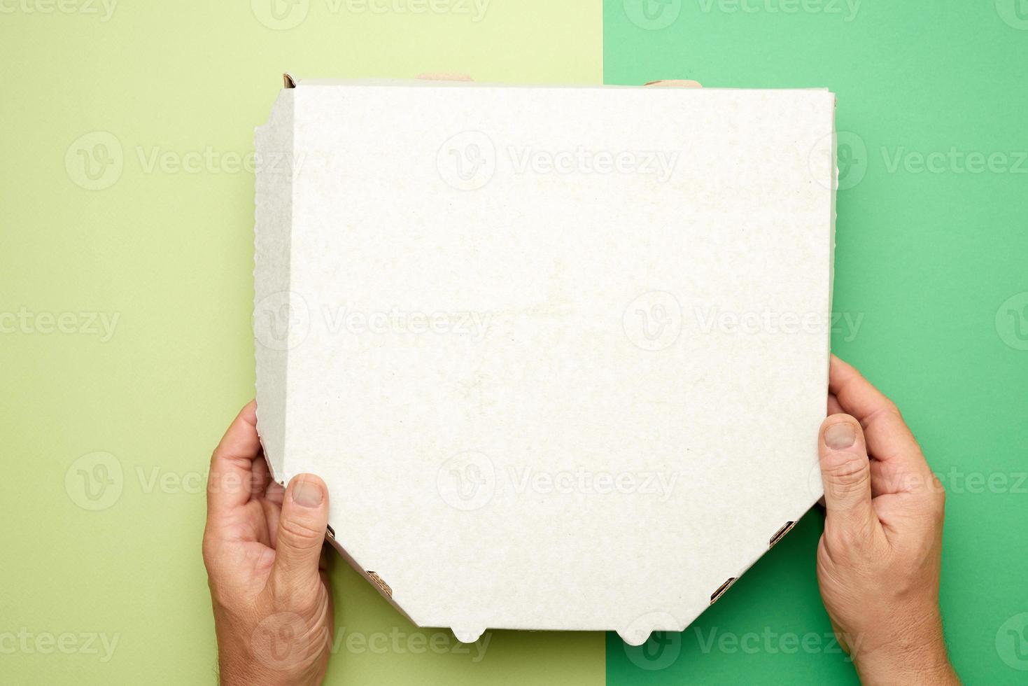 two male hands hold a white cardboard box with pizza photo