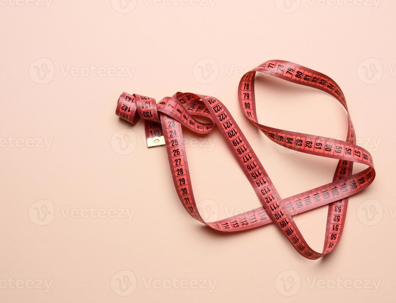 twisted white measuring tape on a beige background photo