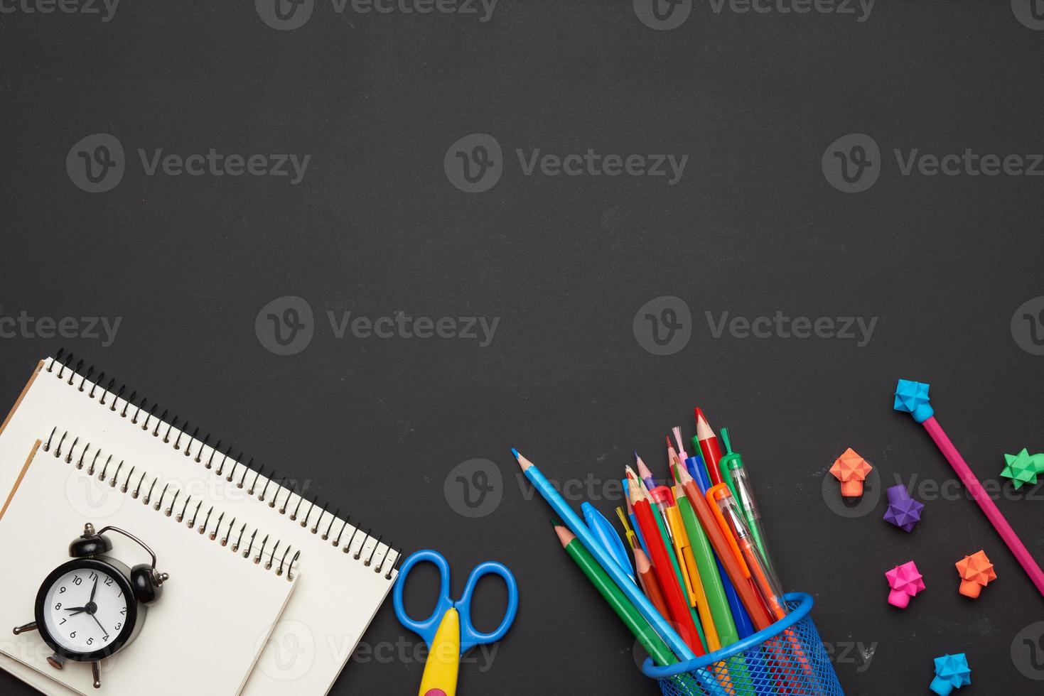 colorful wooden pencils, scissors, notepads on a blank black chalk board photo