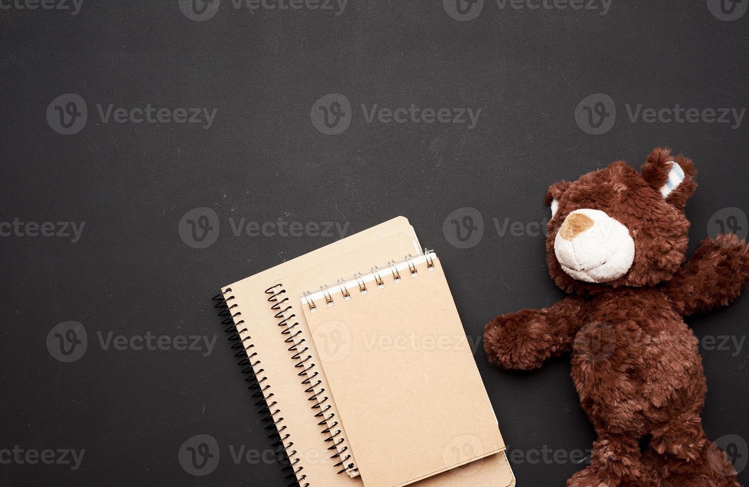 pila de cuadernos con hojas blancas en blanco y un oso de peluche marrón foto