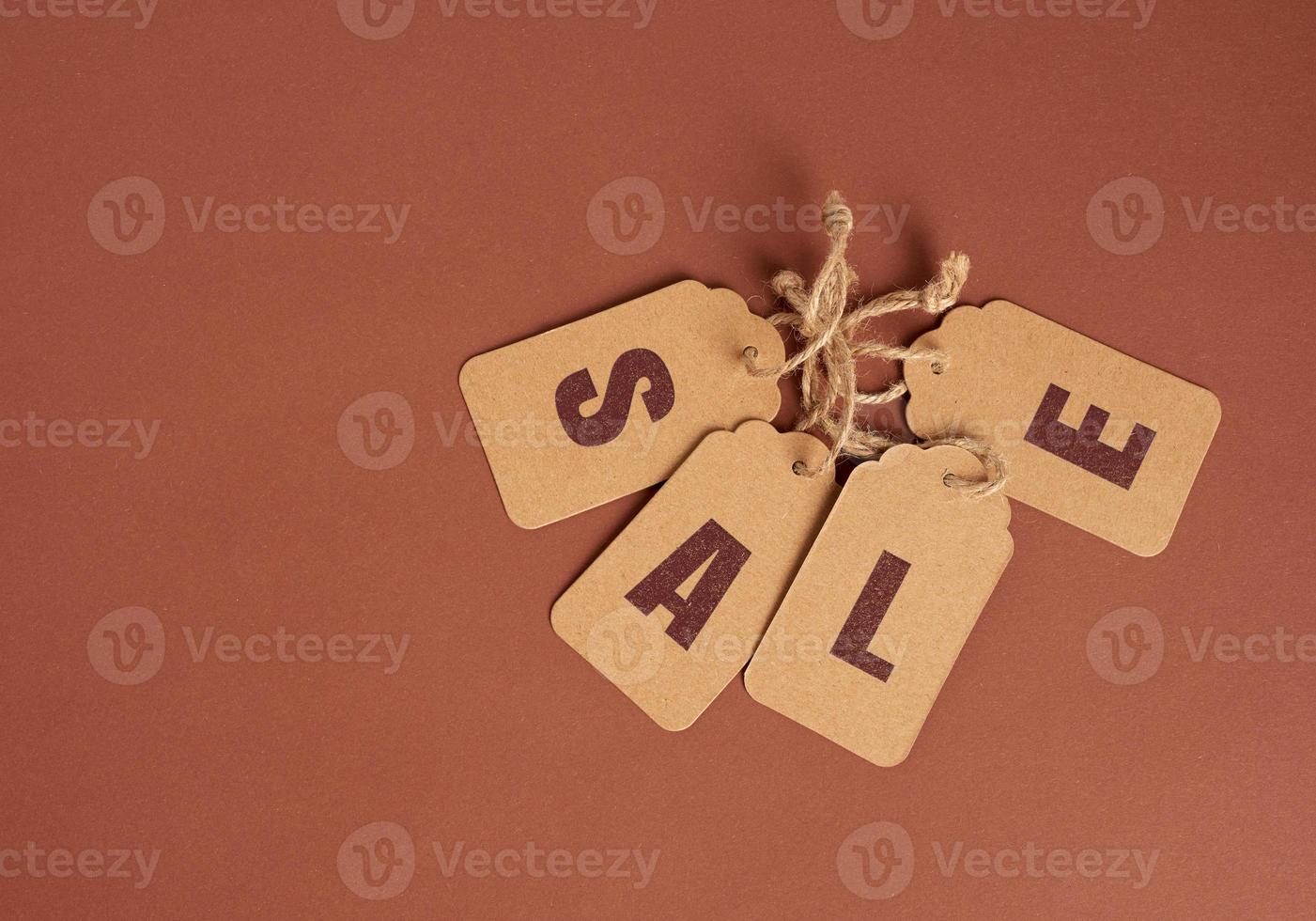 brown paper tags with inscription sale on brown background, seasonal discount concept photo