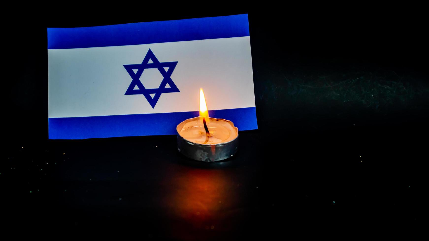 Israeli flag and candles burning in front of it, Holocaust memory day photo