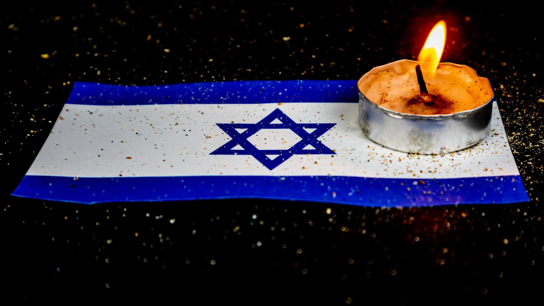 Israeli flag and candles burning above it, Holocaust memory day photo