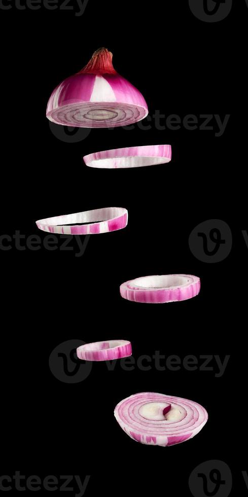 flying rings of sliced purple onion on black background, ingredient for salad photo