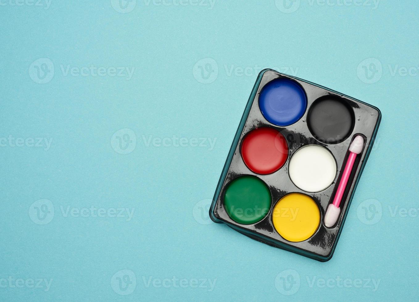palette with multi-colored makeup paints on a blue background photo