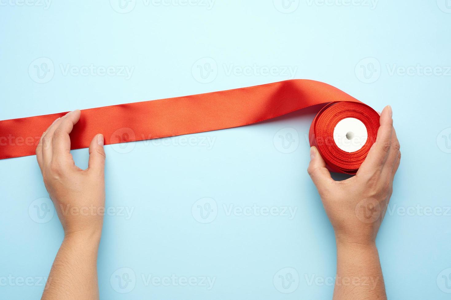 two female hands and red silk ribbons on a blue background photo