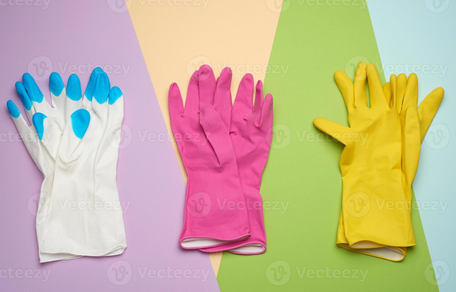 three pairs of protective rubber gloves on a colored background photo
