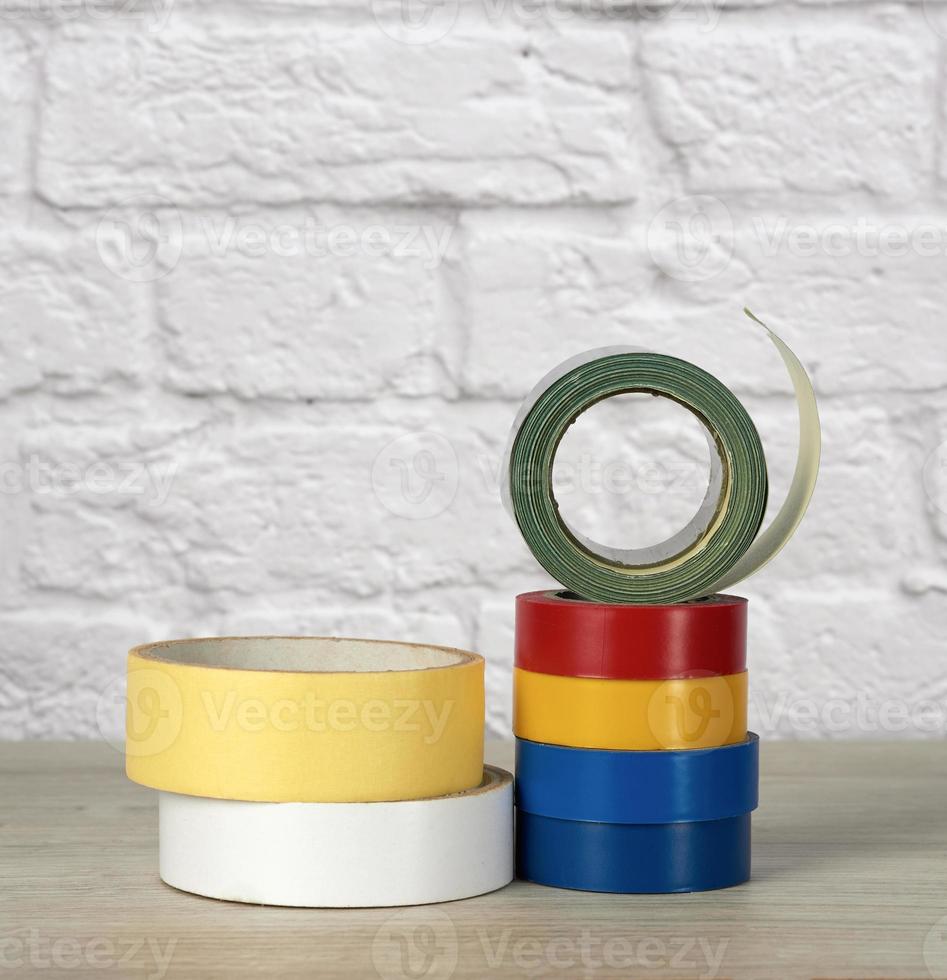 stack of colorful insulating tape on white brick wall background photo