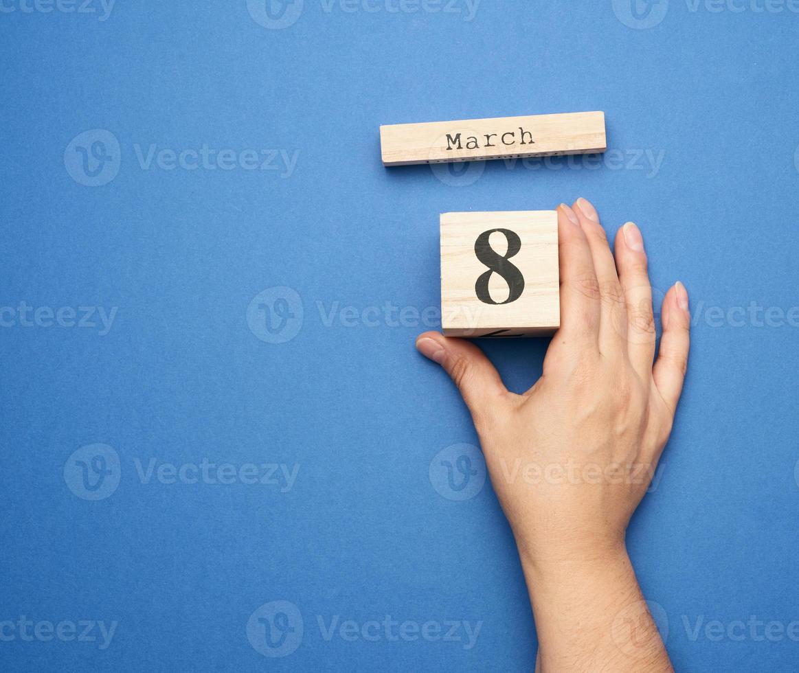 female hand holds wooden calendar with date of eighth march photo