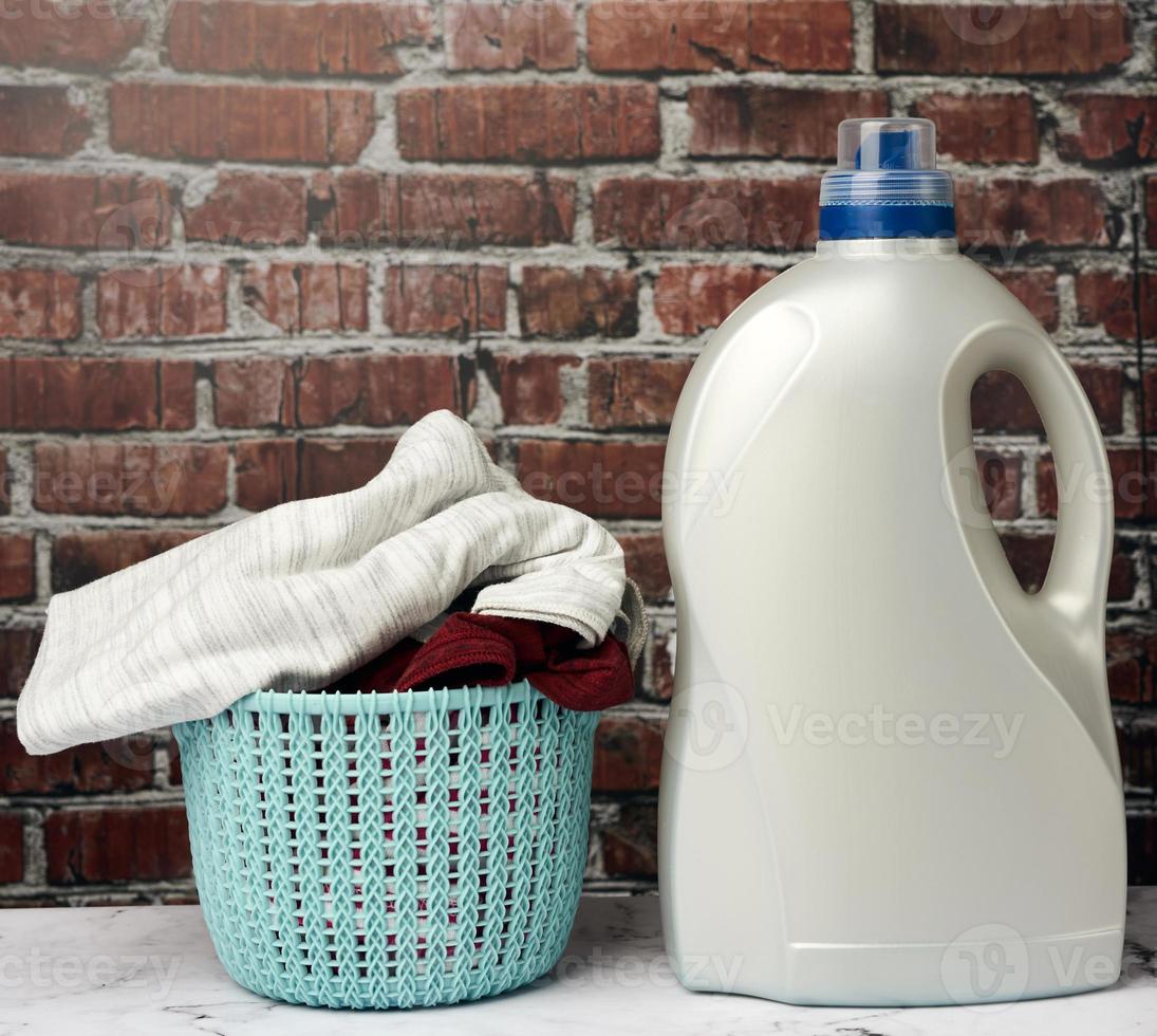 plastic round laundry basket and gray bottle with liquid laundry powder photo