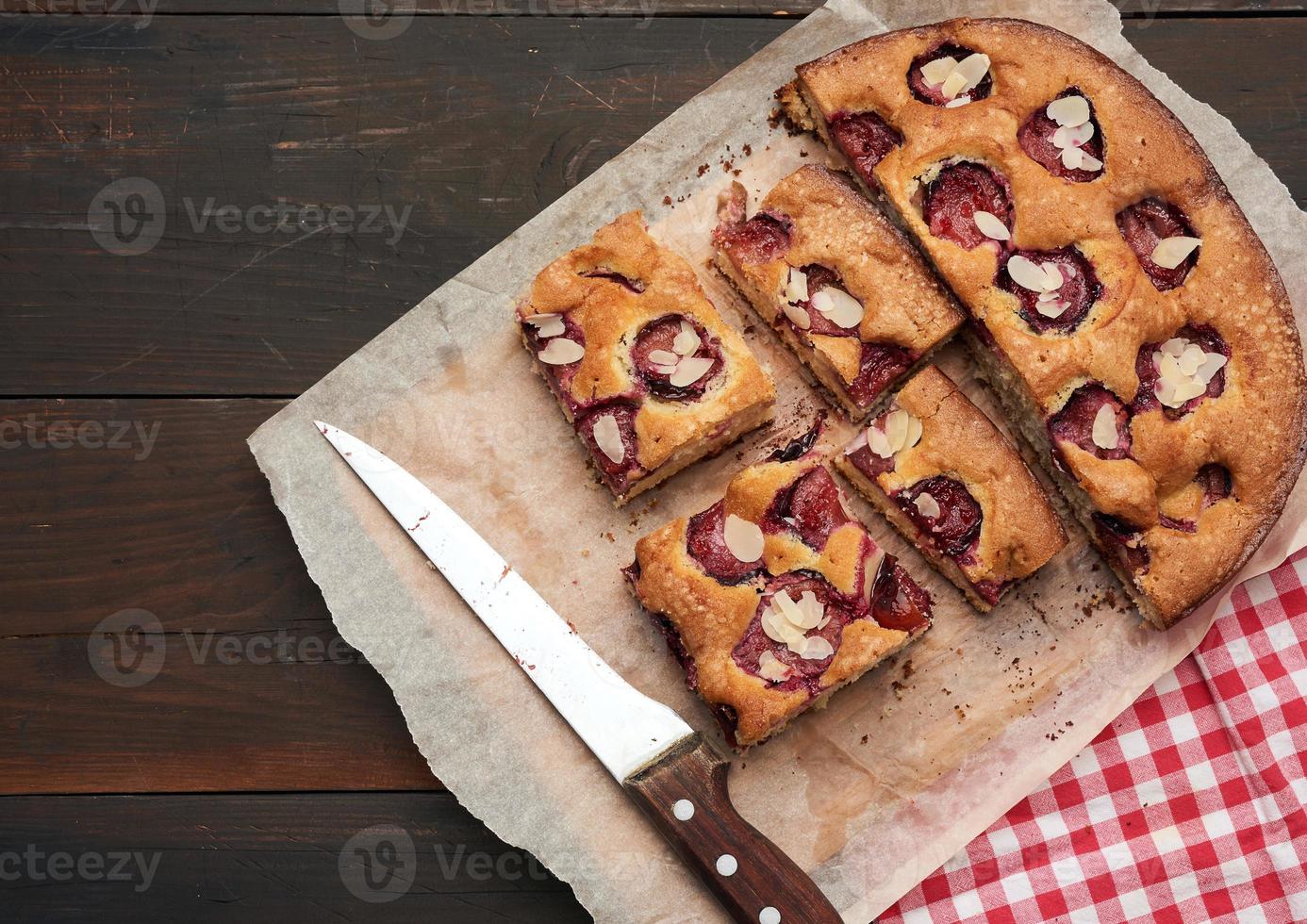sliced baked pie with plums on a wooden plank background photo