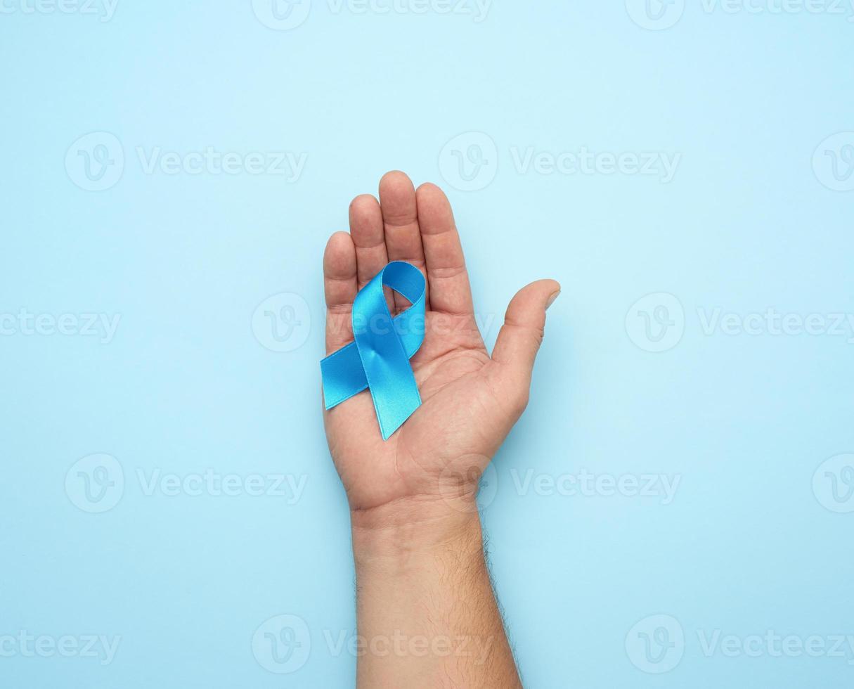 male hand holds blue silk ribbon in the shape of a loop photo