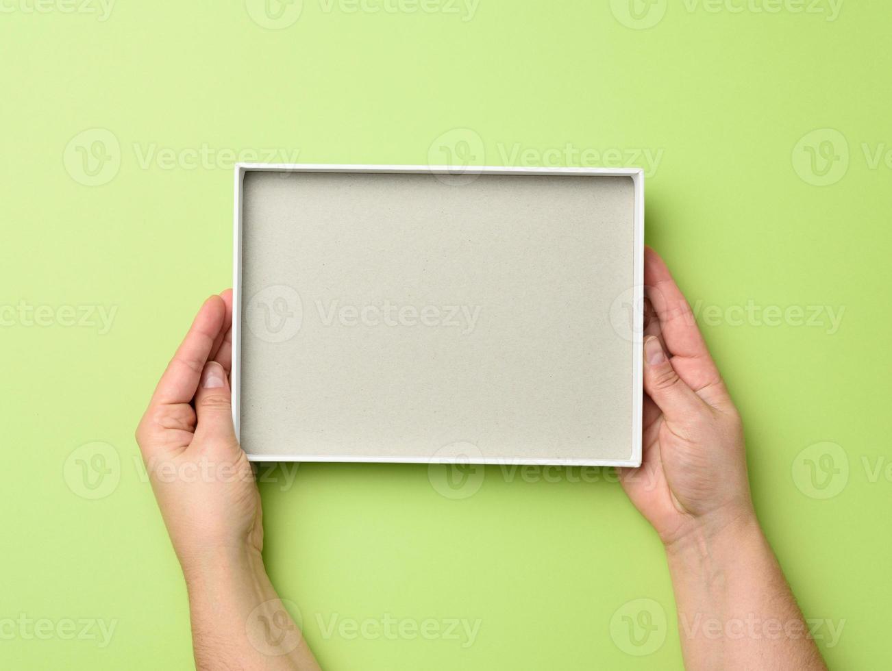two female hands hold an open blank paper box on a green background photo