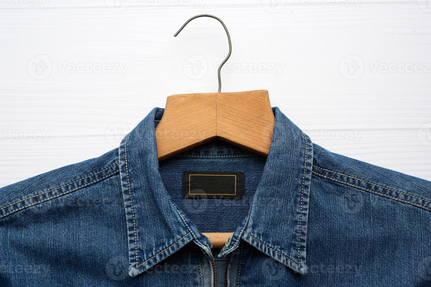 blue denim shirt hanging on vintage wooden hanger, white background photo