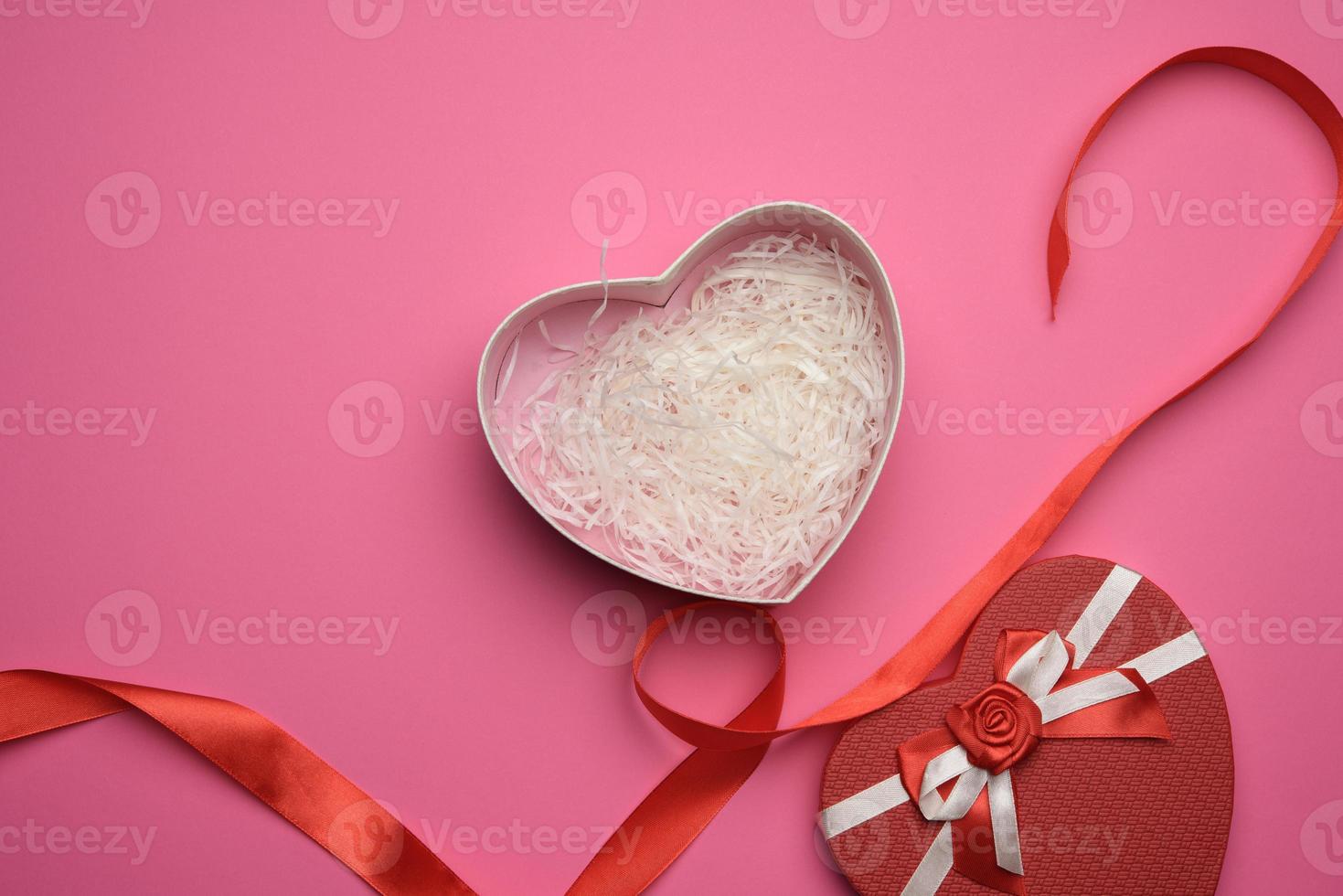 open empty red cardboard box in the form of a heart on a pink background photo