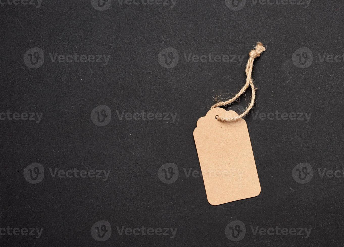 empty paper brown rectangular price tag on a rope on a black background photo