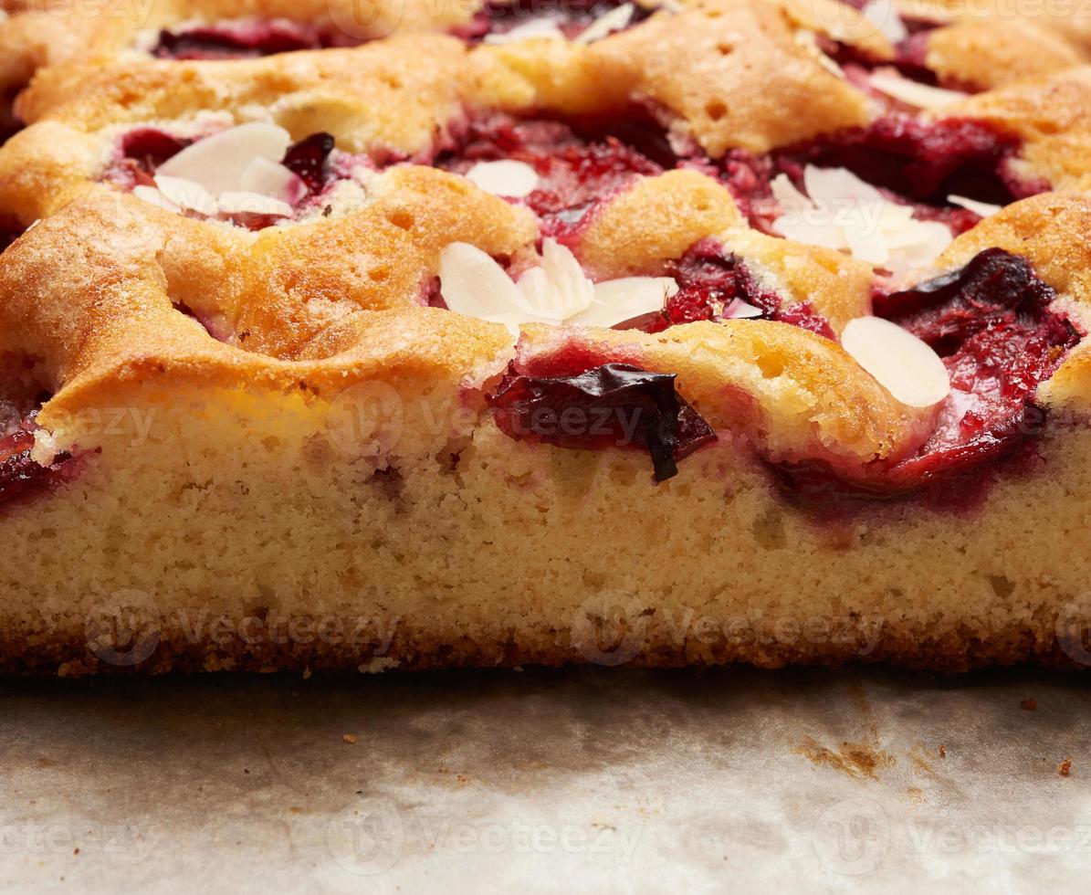 baked slices of sponge cake with plums on brown paper photo