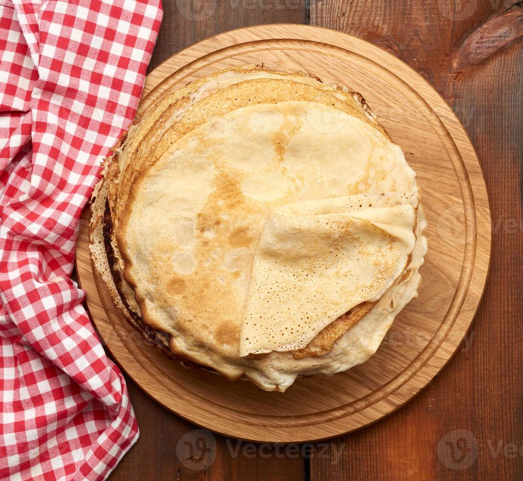 fried round pancakes on a wooden board, brown table photo