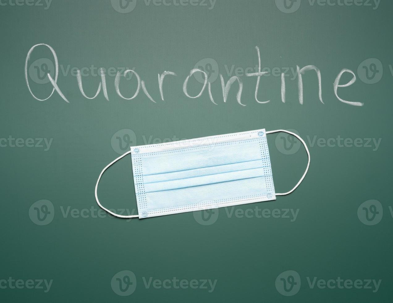 inscription quarantine on a green chalk board and disposable medical mask photo