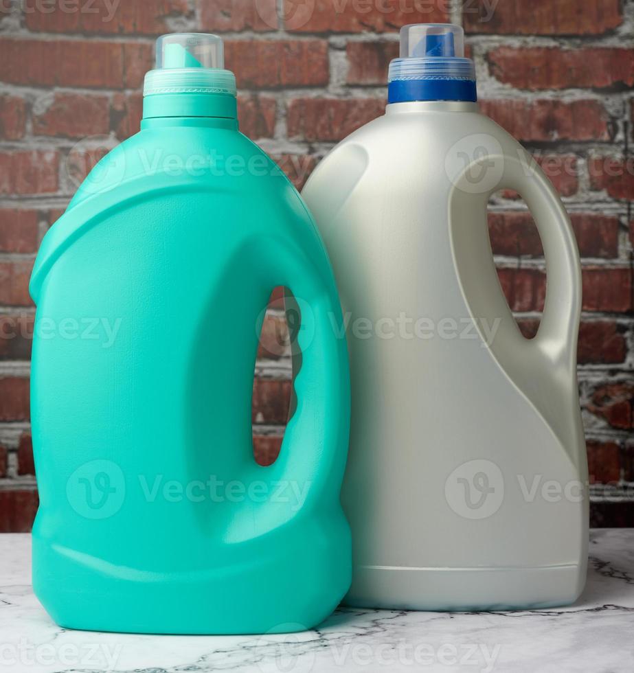 large plastic bottles with liquid detergent on a brown brick wall background photo