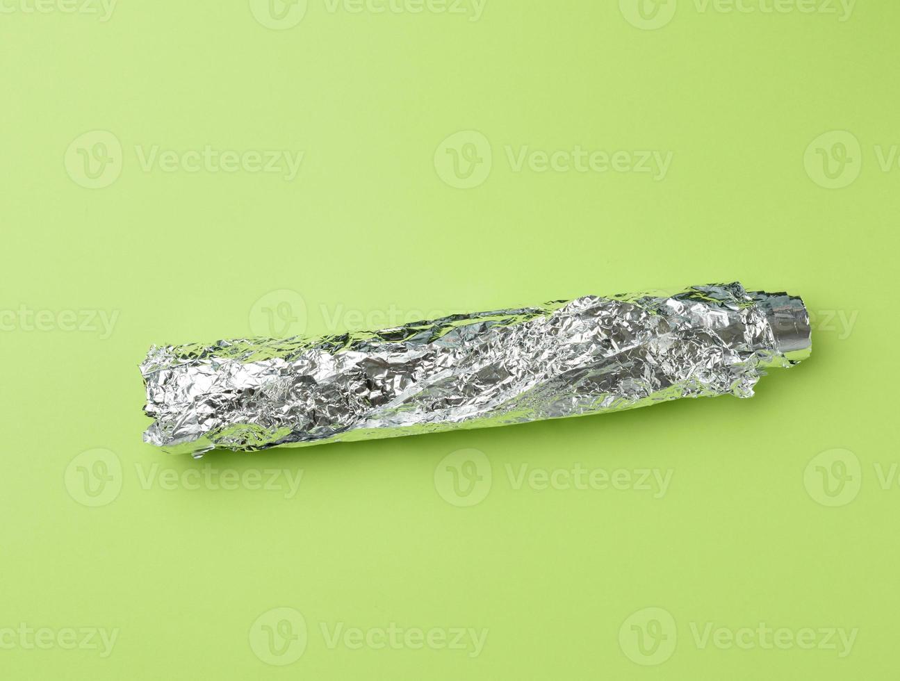 rollo de lámina gris para hornear y envasar alimentos sobre un fondo verde, foto