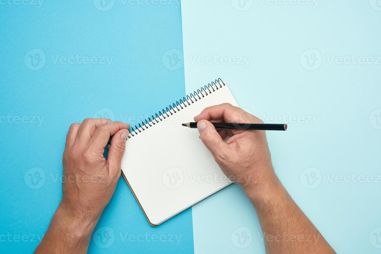two male hands holding open notepad with empty white sheets photo
