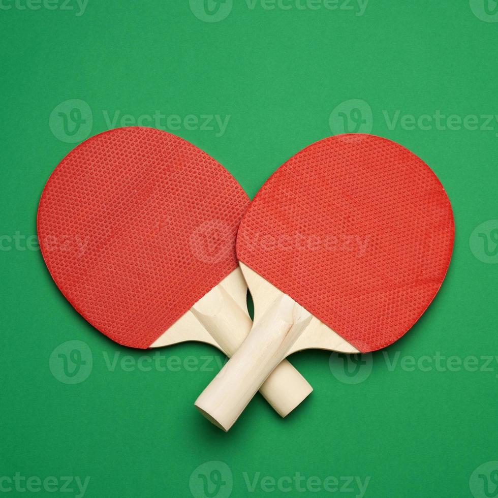 red wooden table tennis racket on green background, pair of ping pong sports tools photo