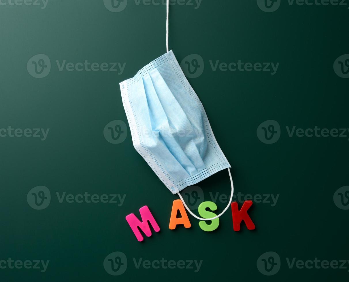 disposable medical mask hanging on blank green chalk board background photo