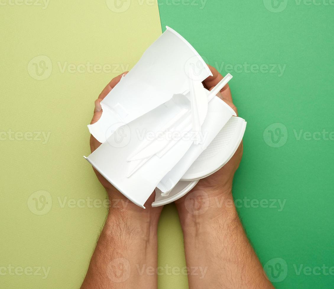hand hold used plastic dishes, pieces of plastic on a green background photo