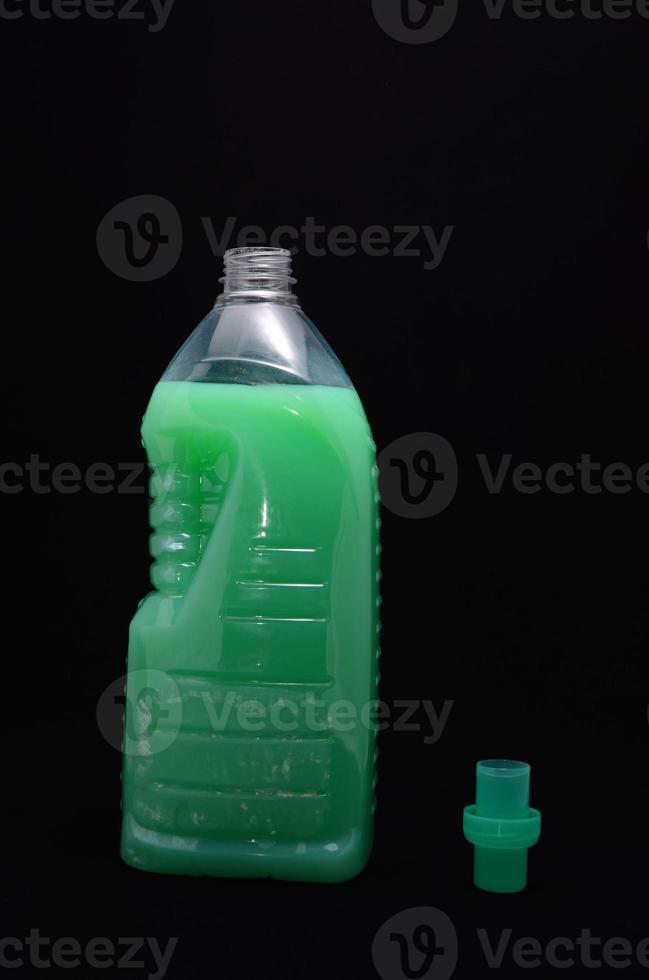 Green cleaning product bottle on black background photo