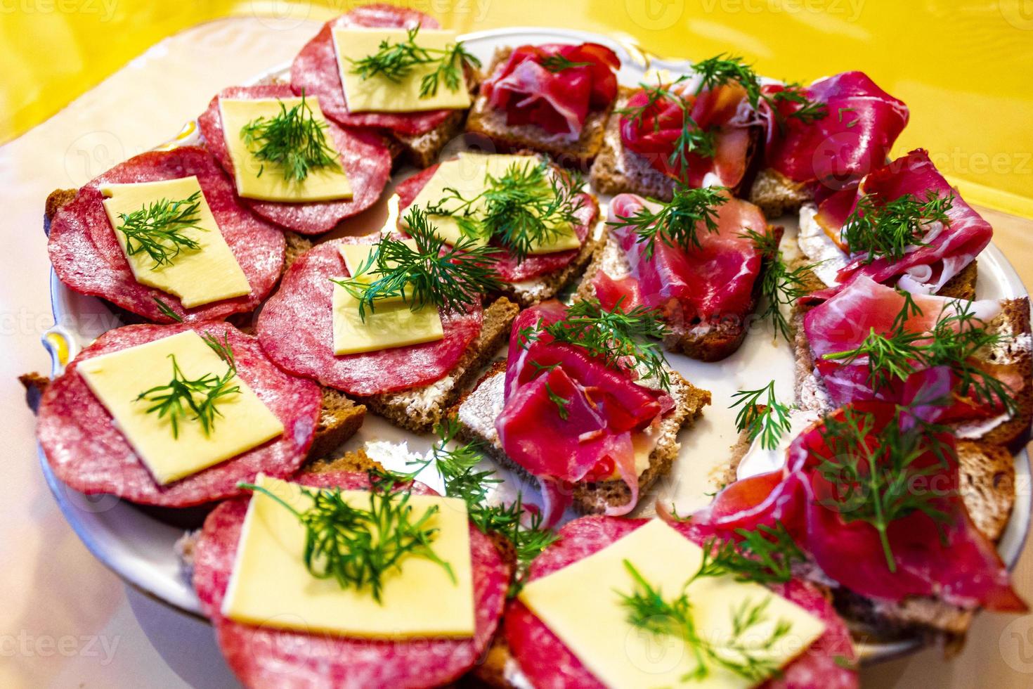 bocadillos pequeños bocadillos salmón queso salami jamón tomate hierbas. foto