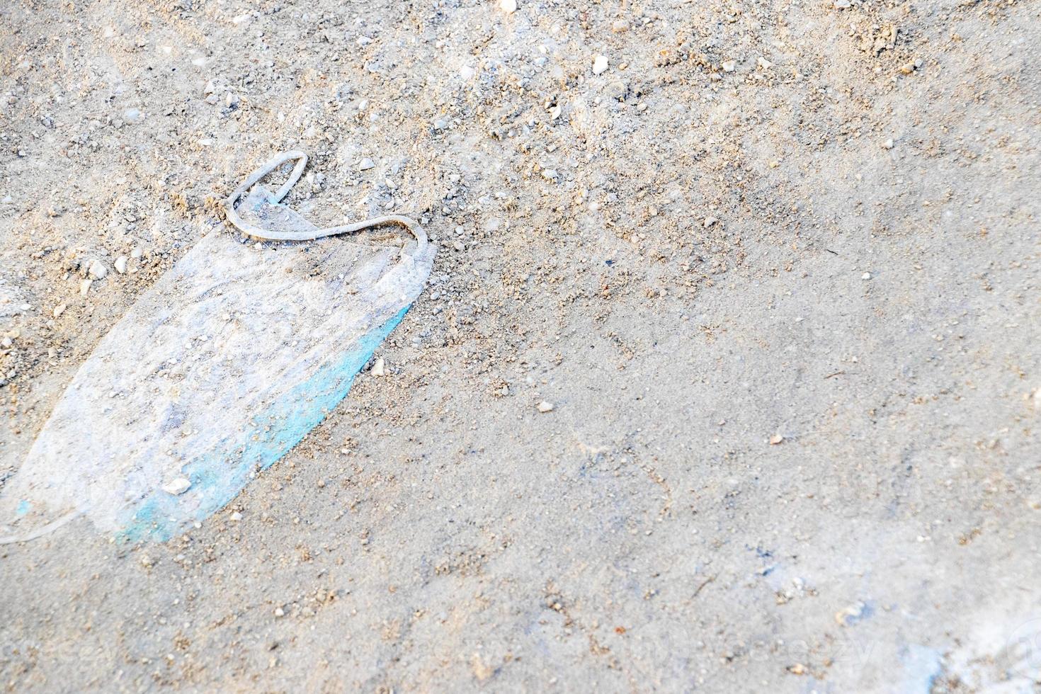 Medical face mask on dirty floor as garbage environmental pollution. photo