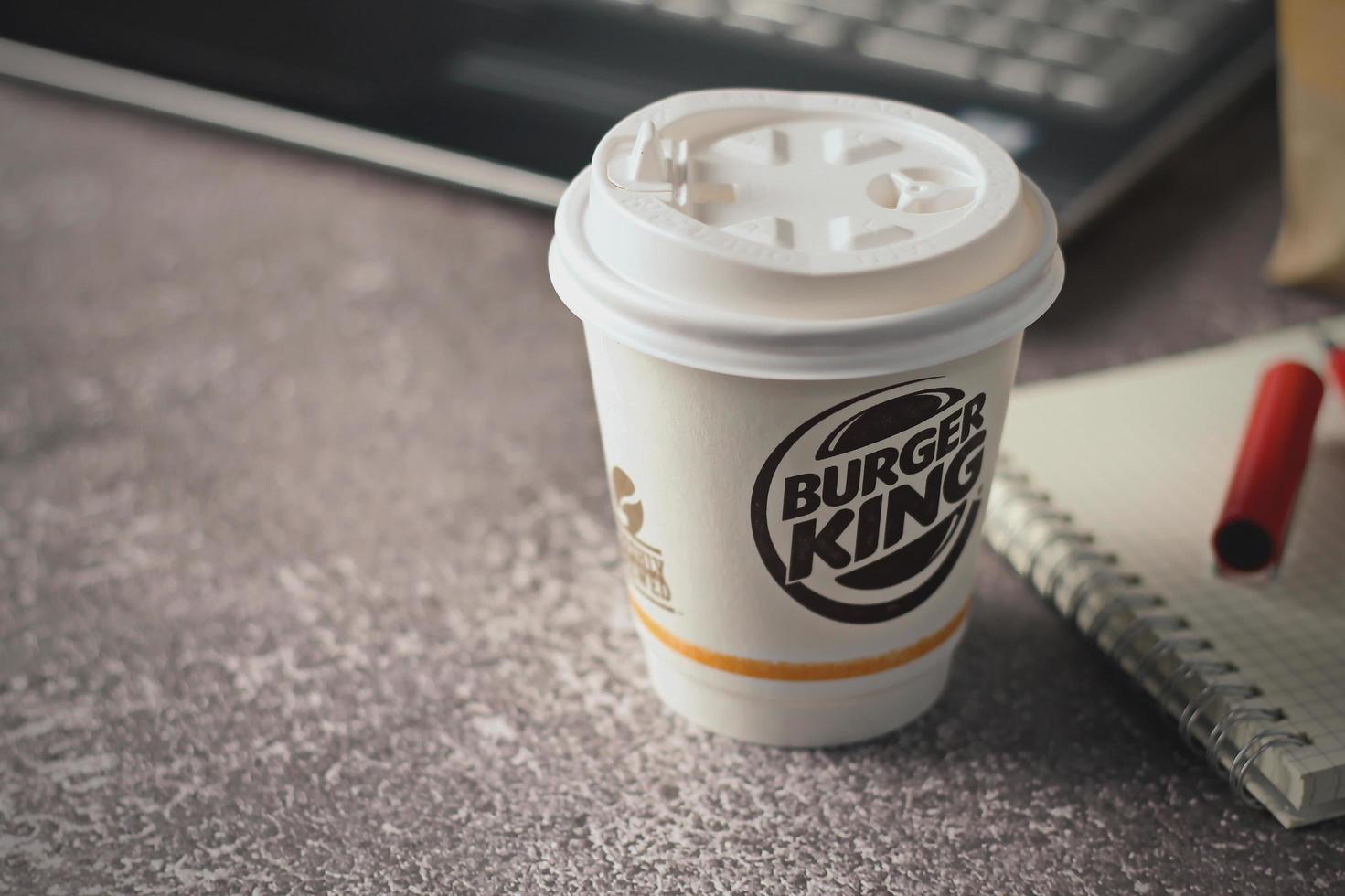 Washington, USA - January 18 2023  Coffee Cup Mug Burger King with notebook and laptop on gray table In studio lighting, Burger King is a popular food in America. photo