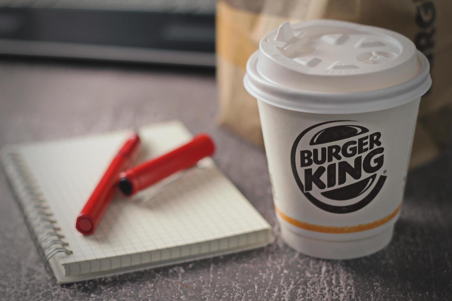 Washington, USA - January 18 2023  Coffee Cup Mug Burger King with notebook and laptop on gray table In studio lighting, Burger King is a popular food in America. photo